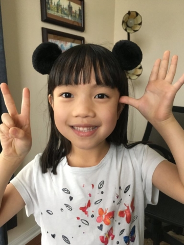 Smiling girl makes gives a peace sign.