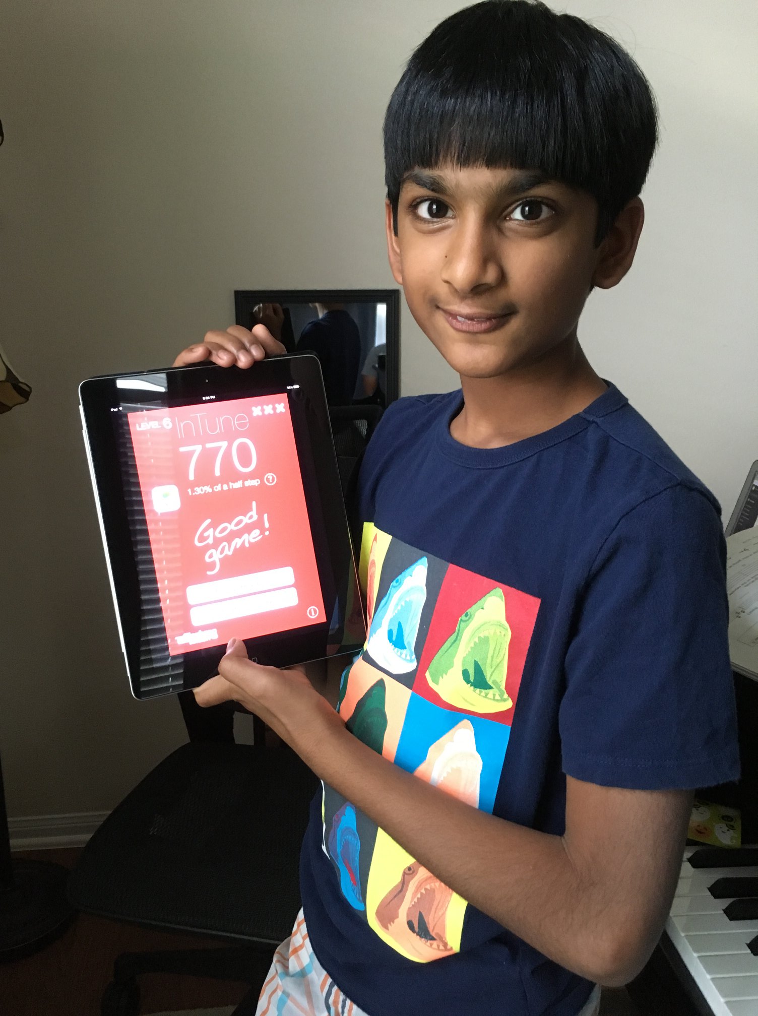 Middle school boy holds an iPad showing a high score for ear training.