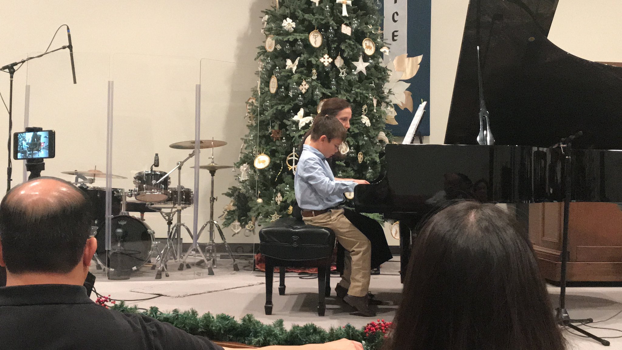 Young boy plays a piano duet with his teacher at a church.