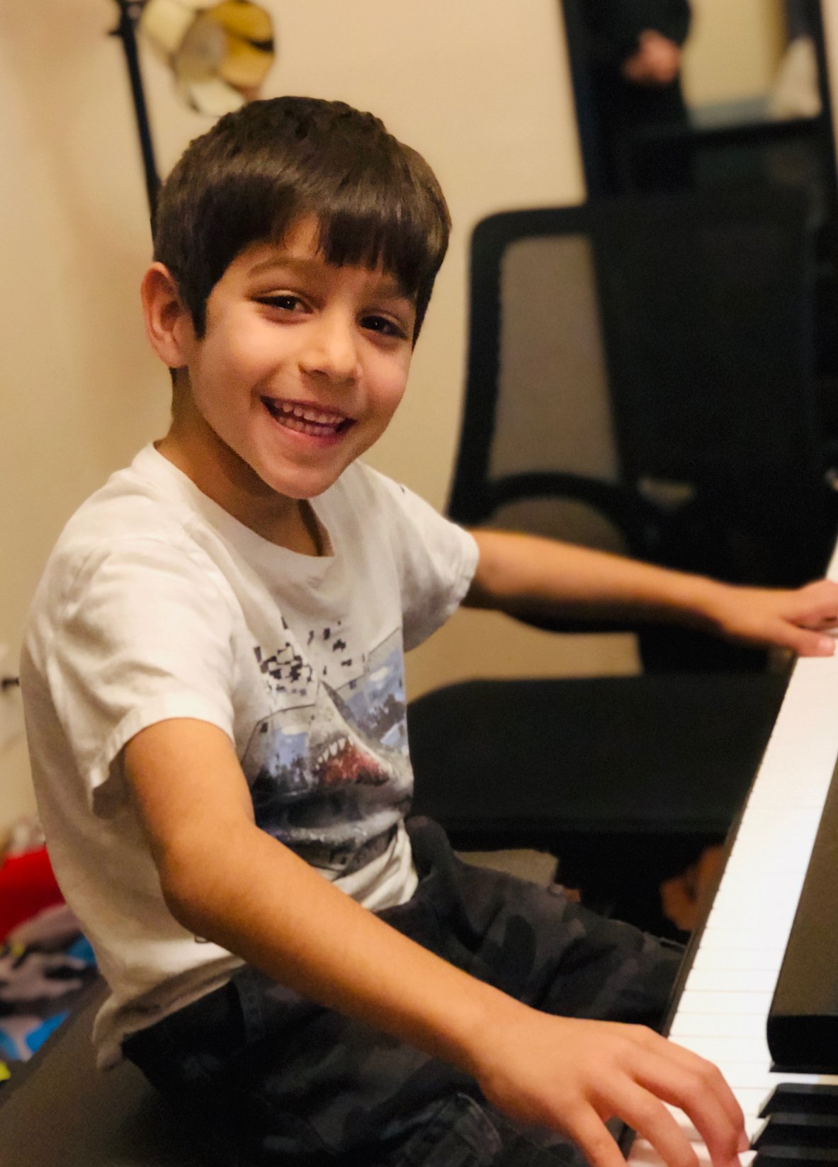 First grade boy smiles while playing the piano.